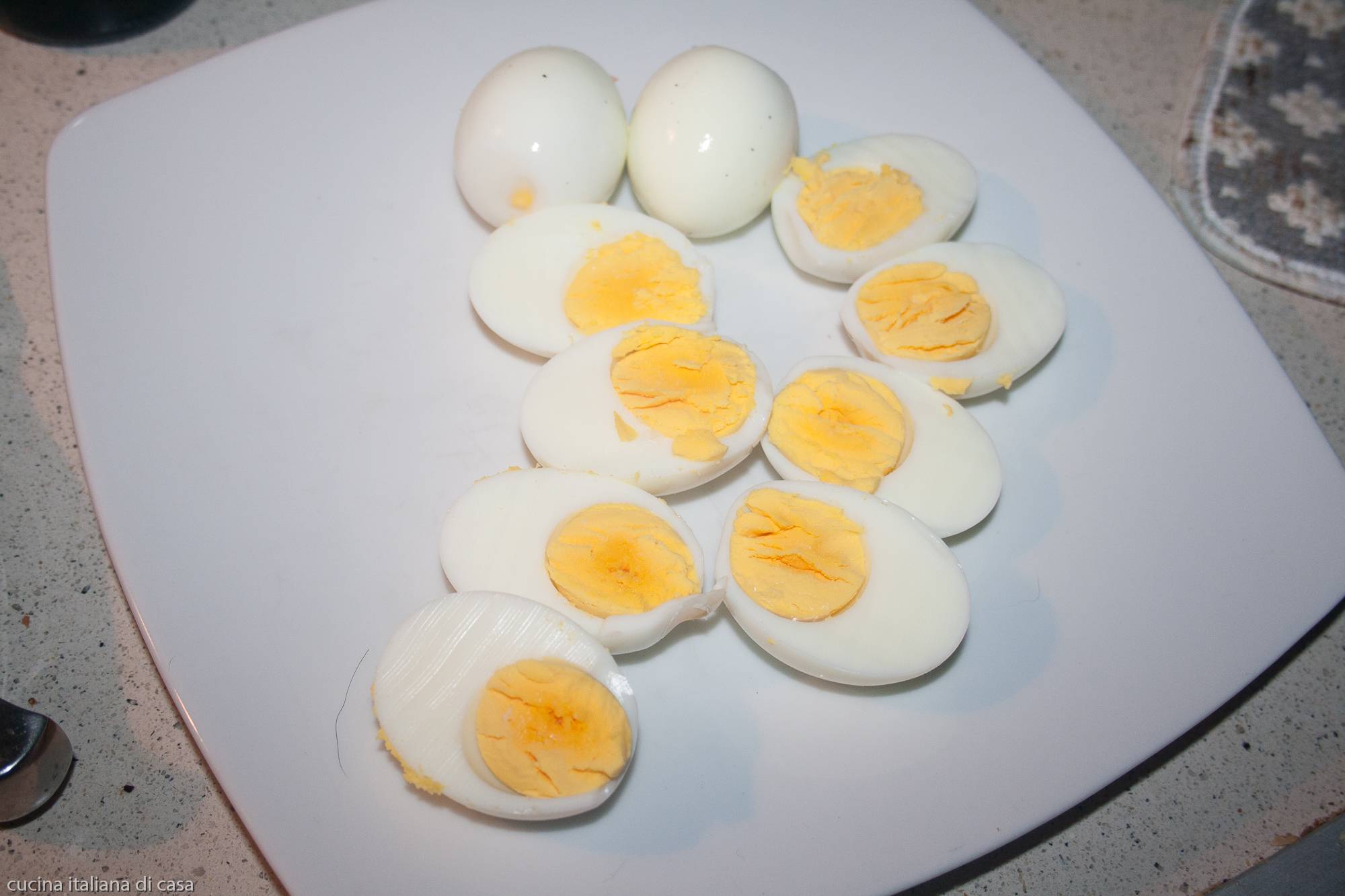uova lessate tagliate a metà su piatto bianco viste dall'alto