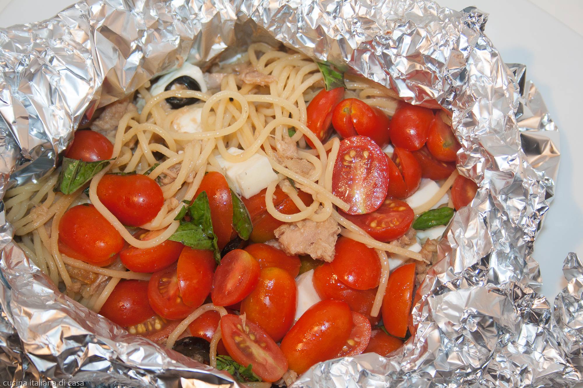 spaghetti al cartoccio con tonno e pomodorini serviti